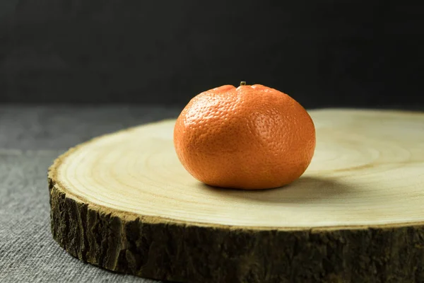 Fresh juicy orange on a wooden stand. An orange on a wooden stand on a dark background. Vitamin C. Copy space