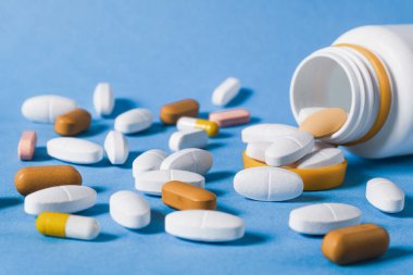 Masaya saçılmış beyaz renkli haplar, yakın plan. Masada kapsül şeklinde bir sürü hap var. Haplar şişeden döküldü. Boşluğu kopyala