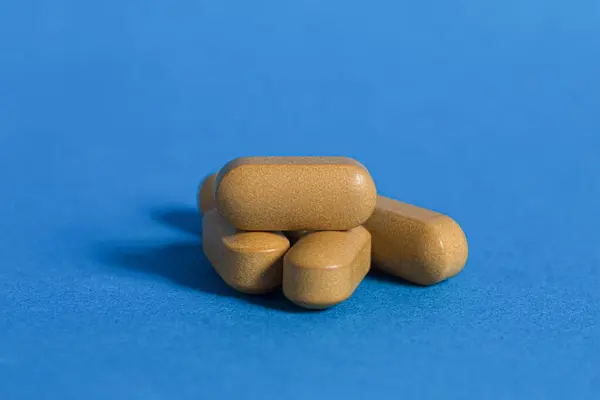 青い背景に茶色の錠剤 接近中だ 錠剤カプセル 医療および栄養補助食品 スペースのコピー — ストック写真