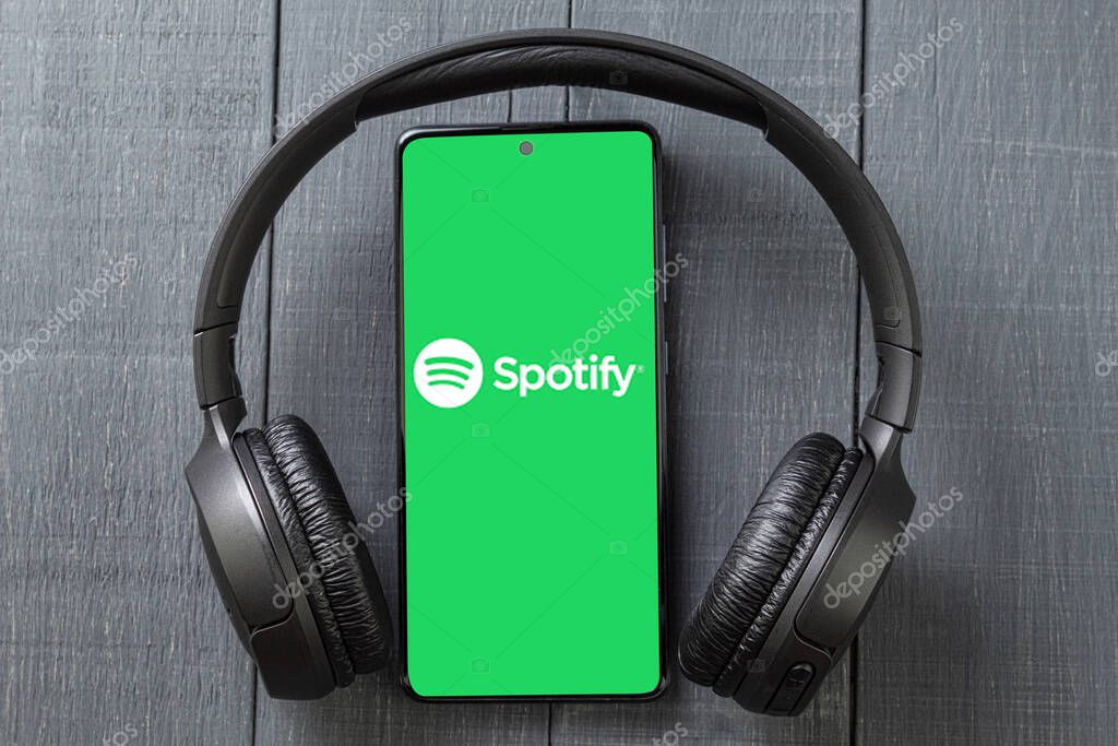 Warsaw, Poland - May 14, 2023: Wireless headphones and phone, Spotify app, background. Copy space