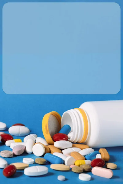 多くの薬がペットボトルからこぼれた 青い背景にペットボトルからこぼれる多色の錠剤 薬や薬の様々な 医学的概念 コピースペース — ストック写真