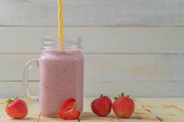 Çilekli taze milkshake. Bir bardak taze çilekli milkshake. Hafif ahşap arka planda taze çilekli püre. Sağlıklı yiyecek ve içecek konsepti