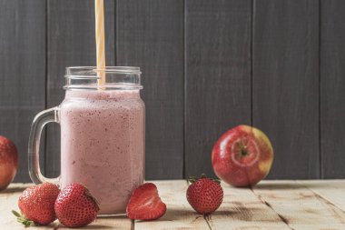 Çilekli taze milkshake. Bir bardak taze çilekli milkshake, püre ve ahşap arka planda taze çilek. Sağlıklı yiyecek ve içecek konsepti