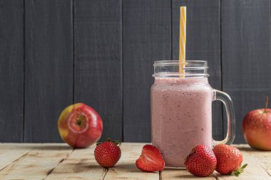 Çilekli taze milkshake. Bir bardak taze çilekli milkshake, püre ve ahşap arka planda taze çilek. Sağlıklı yiyecek ve içecek konsepti