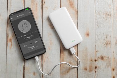 Telefondaki oyuncu, ahşap bir arka planda. Uzayı kopyala Kulaklıkla müzik çalan akıllı telefon. Yayınlanan radyo yayın konsepti