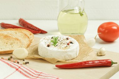 Fransız peynirinin fırında pişirilmeye hazır yakın çekimi. Koyu ahşap bir arka planda, ahşap bir tahtanın üzerinde kızarmış ekmeklerle servis edilir.