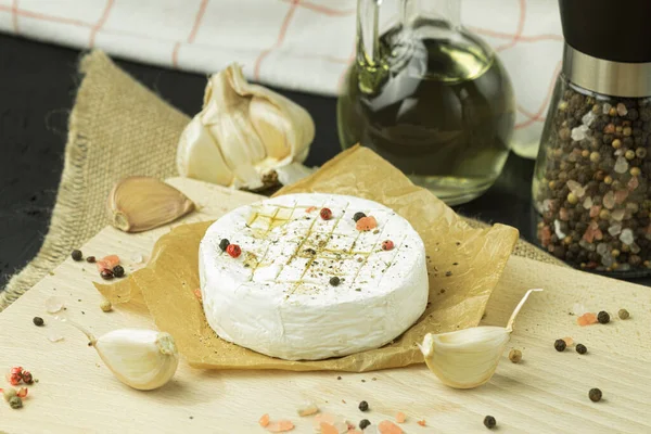 stock image Close-up of French camembert cheese ready to be baked in the oven. Served with croutons on a wooden board on a dark wooden background, top view