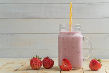 Çilekli taze milkshake. Bir bardak taze çilekli milkshake. Hafif ahşap arka planda taze çilekli püre. Sağlıklı yiyecek ve içecek konsepti