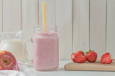 Çilekli taze milkshake. Bir bardak taze çilekli milkshake. Hafif ahşap arka planda taze çilekli püre. Sağlıklı yiyecek ve içecek konsepti