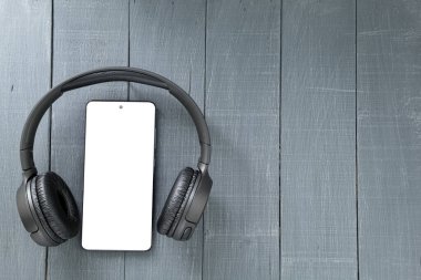 Beyaz ekranlı cep telefonu, tasarımcı için boş. Kulaklıklı akıllı telefonun en iyi görüntüsü. Boşluğu kopyala