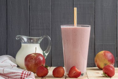 Çilekli taze milkshake. Bir bardak taze çilekli milkshake, püre ve ahşap arka planda taze çilek. Sağlıklı yiyecek ve içecek konsepti