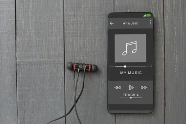 Kablolu kulaklıklar ve masada bir telefon. Cep telefonu ve kulaklıklar, çalgıcıda müzik çalıyor. Yakın plan. Ekrandaki oyuncu, boşluğu kopyala