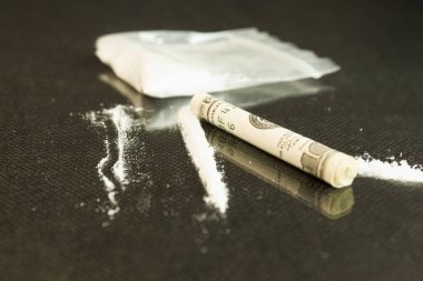Beyaz toz masanın üzerine saçıldı. Beyaz toz, paranın yanındaki cam masaya saçıldı. Fatura bir tüpe sarıldı.
