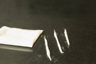 Beyaz toz masanın üzerine saçıldı. Beyaz toz, paranın yanındaki cam masaya saçıldı. Fatura bir tüpe sarıldı.