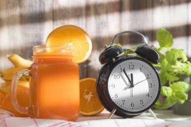 Mutfak masasında taze portakal suyu. Bardakta portakal suyu, masada taze meyve ve nane. Boşluğu kopyala