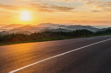 Dağlık bir bölgede bir yol. Güzel dağ manzarası. Dağlık bölgedeki otoyolun manzarası. Güzel bir arka plan. Güzel doğada yol manzarası. Gün batımı, gün doğumu