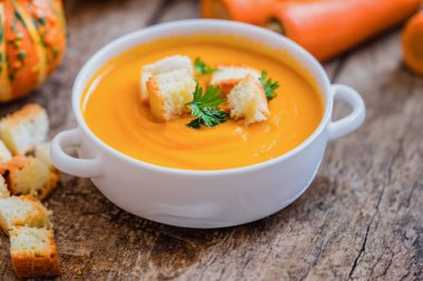 Lezzetli balkabağı kremalı çorba ve ahşap arka planda sonbahar yapraklı kompozisyon