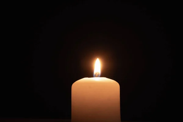 stock image A memorial candle on a dark background. Burning candle on black background, copy space.