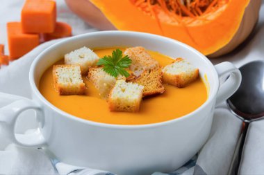 Lezzetli balkabağı kremalı çorba ve ahşap arka planda sonbahar yapraklı kompozisyon