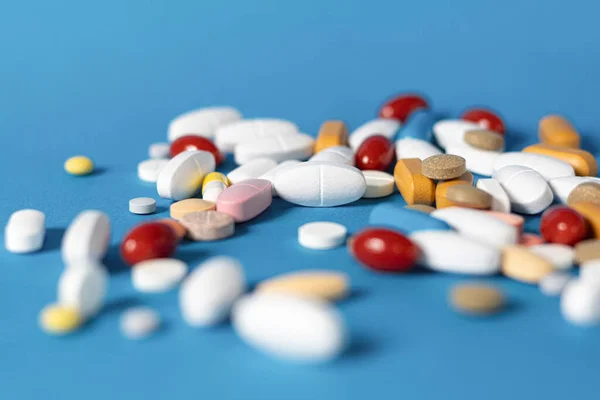 Pills on a blue, medical background. Pile of medicine pills. Background with colorful pills and capsules. Copy space