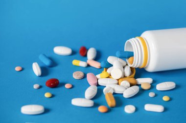 Yakın plan, haplar masaya saçılmış. Farklı renk ve şekillerde bir sürü hap. Antibiyotikler, ağrı kesiciler ve antibiyotikler. Kopyalama alanı olan arkaplan