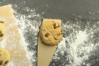 Ev yapımı çikolatalı kurabiyeler. Yukarıdan bak. Gri bir masada bir yığın lezzetli çikolata parçalı kurabiye. Boşluğu kopyala