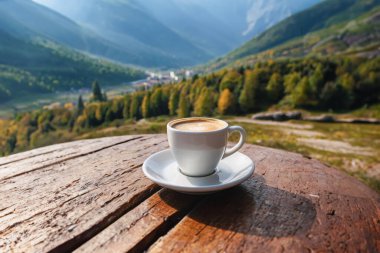 Masanın üzerinde bir fincan kahve. Dağların arkasında beyaz bir fincan kahve. kopyalama alanı. YZ oluşturuldu,