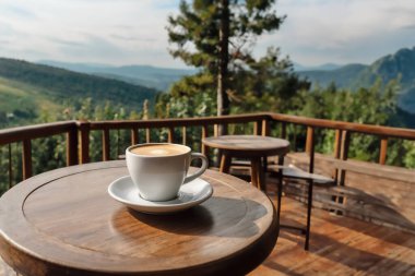 Masanın üzerinde bir fincan kahve. Dağların arkasında beyaz bir fincan kahve. kopyalama alanı. YZ oluşturuldu,