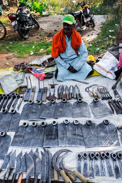 Bastar, Chhattisgarh, India / November 23, 2021: A tribal man sells wrought iron agricultural tools at Haat (weekly) market.