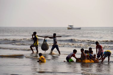 Mumbai, Hindistan / 10 Eylül 2017: Güney Asyalı Hintli balıkçılar Uttan Sahili 'nde satılmak üzere denize demirlemiş teknelerinden bir sürü balık taşıyorlar. 
