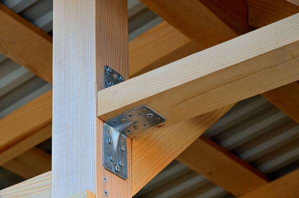 Close-up of wooden elements and metal connectors in a roof truss structure in a frame construction industry