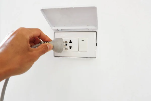 Man's hand holding a power plug to plug it into a socket