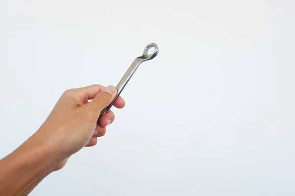 Man\'s hand is holding a ring spanner to tighten something.