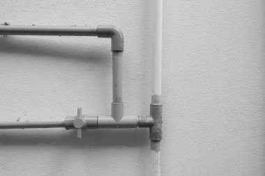 Evin içindeki su sisteminin yol açtığı beton duvardan çıkan PVC borular..