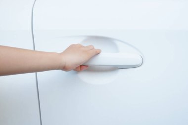 Bir çocuğun eli beyaz bir arabanın kapısını açmak için jest yapıyor..