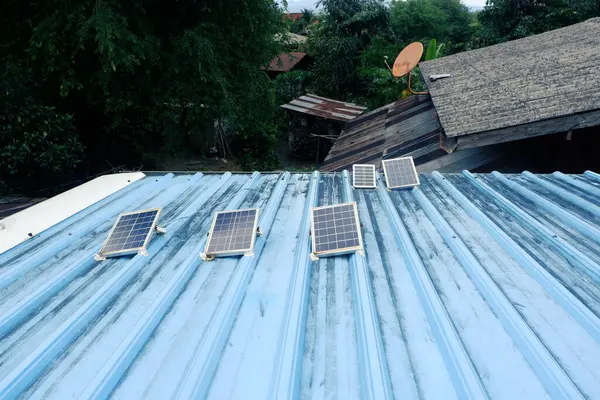 Kırsal bir evin mavi metal çatısına kurulmuş küçük güneş panelleri.