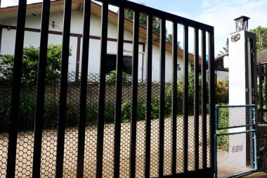 Evin önündeki demir kapı ve köpekleri uzak tutmak için küçük bir PVC kapısı.