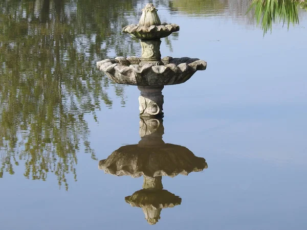 A small fountain and its reflection in the water