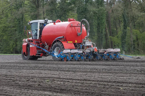 春天在荷兰东部的可耕地上种植玉米的浆液注射器 图库照片