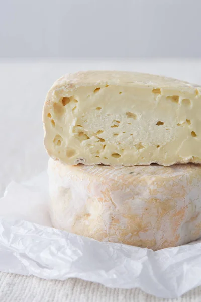 フランスの柔らかい強い香りのチーズマンスター上の白い紙の上に軽い素朴な背景 選択的な焦点 — ストック写真