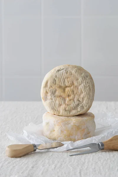 French soft strong smelling cheese Munster on white paper on light rustic background, selective focus