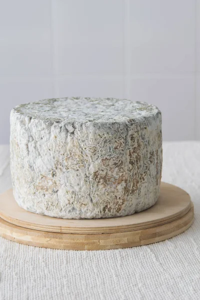 ライトの背景に木製のまな板上の丸みを帯びた青いチーズホイール 選択的な焦点 — ストック写真