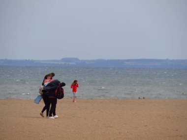 Mother and children on the beach with the North Norfolk coast in the distance. Skegness UK