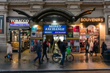 İnsanlar gün batımında Piccadilly 'de dükkanların önünden geçiyorlar.