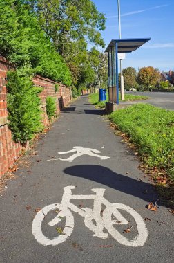 Kaldırımdaki bir otobüs durağının yanında bisiklet ve yaya işaretleri var.