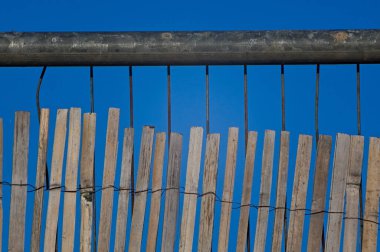 Mavi gökyüzü arkaplanlı, bambu kaplı metal bir çiti kapatın.