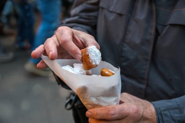 Elinde bir kese dolusu Mutzenmandeln, pudra şekerle kaplanmış bol yağda kızartılmış tatlı hamur işi Noel, Yeni Yıl ve Karnaval 'da geleneksel Alman ziyafeti çeken bir adamın elleri. Kopya alanı.