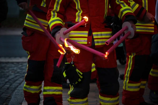 stock image Firefighters lighting torches for a traditional procession of lights on St. Martin's Day at night, selected focus, narrow depth of field