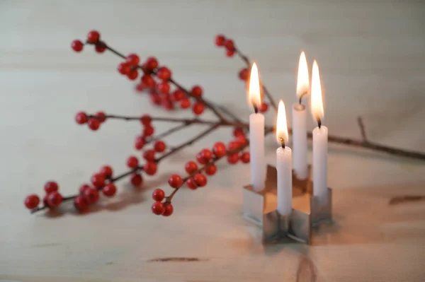 小小的花环 四个小蜡烛放在一个星形的饼干切割机上 在一根冬青枝头前面 木桌上挂着红色的浆果 精选的焦点 狭窄的田野深度 — 图库照片