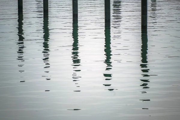 Schwarze Anlegestapel Oder Delfine Mit Spiegelung Wasser Einem Leeren Yachthafen — Stockfoto